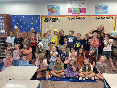 A fifth grade class making silly faces as the pose for a picture 