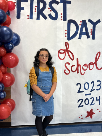 Student standing in front of first day of school sign 
