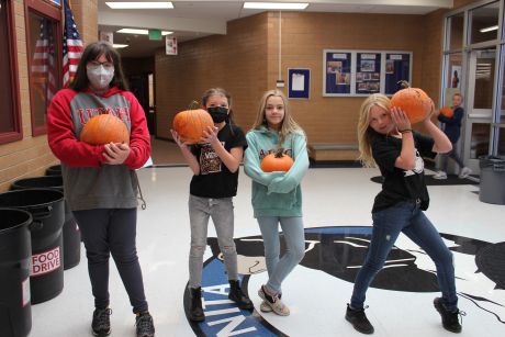 three students holding pumpkins