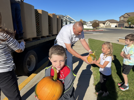 Mr. Andersen handing a student a pumpkin